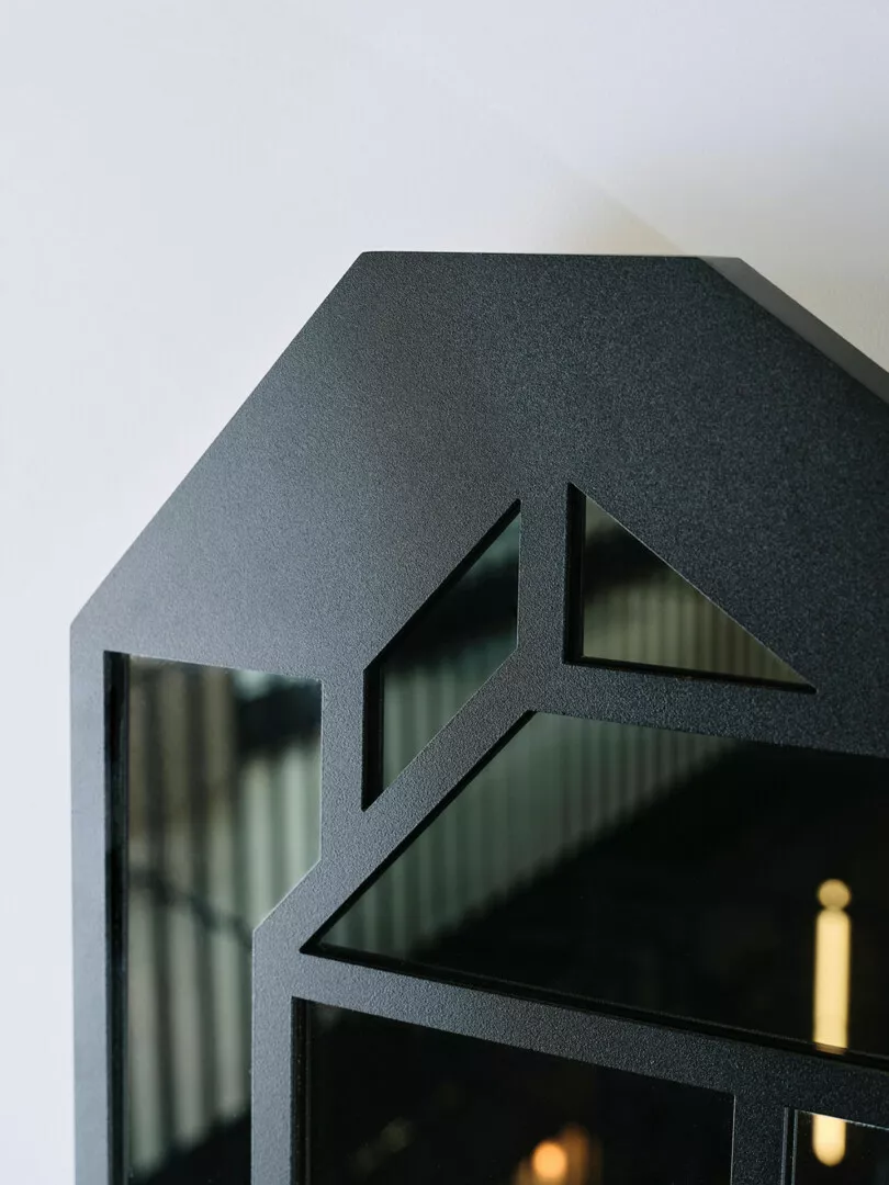 Black house-shaped décor item against a light background.