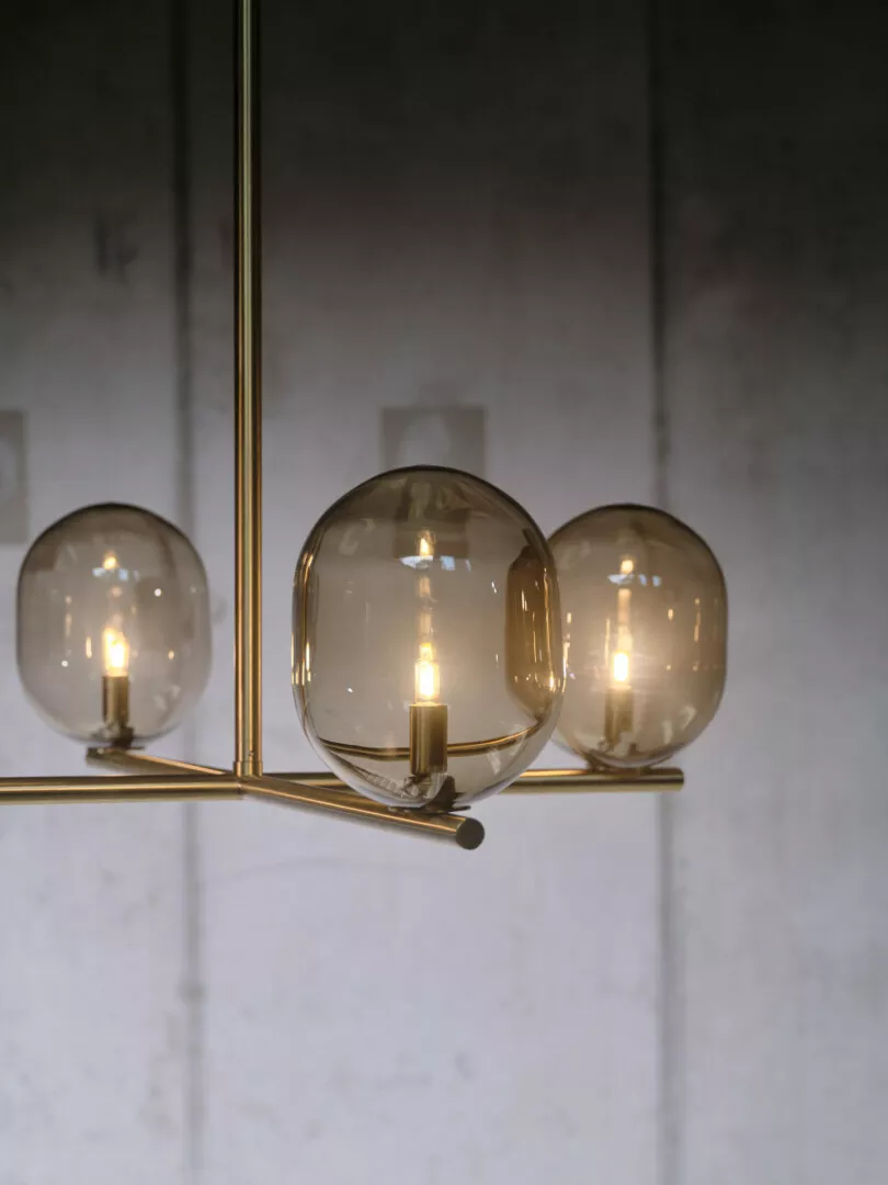 Modern gold chandelier with illuminated round glass bulbs.