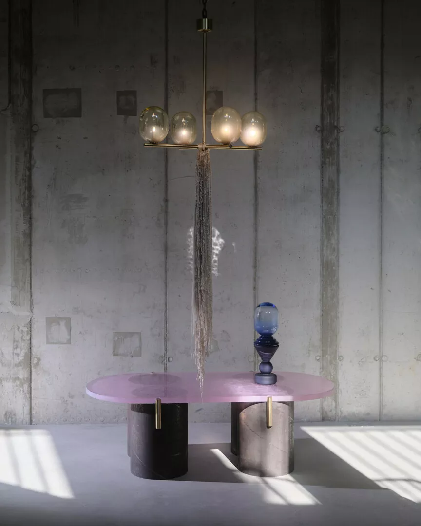 Modern interior with stylish chandelier and pink oval table.