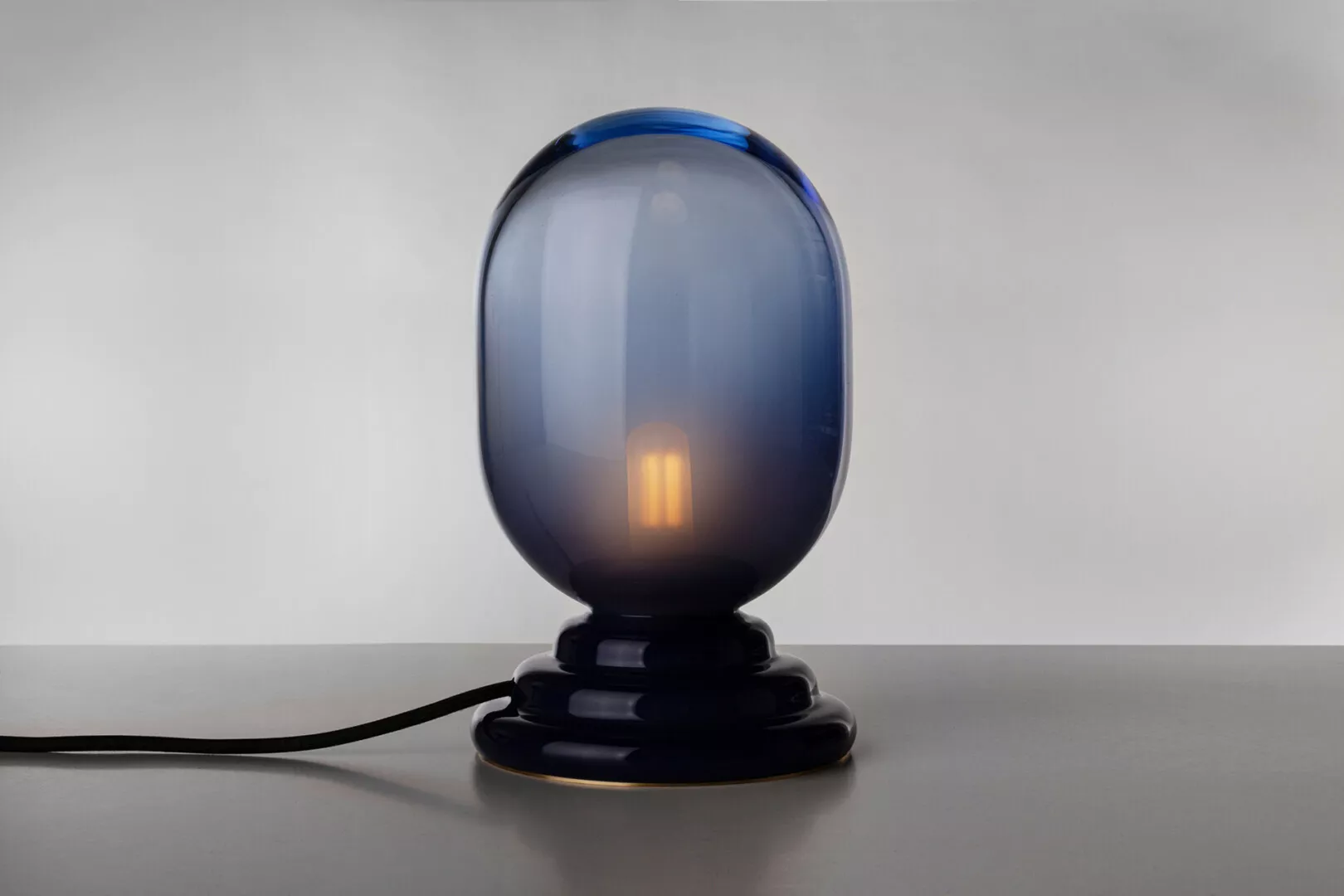Blue glass table lamp with illuminated bulb.