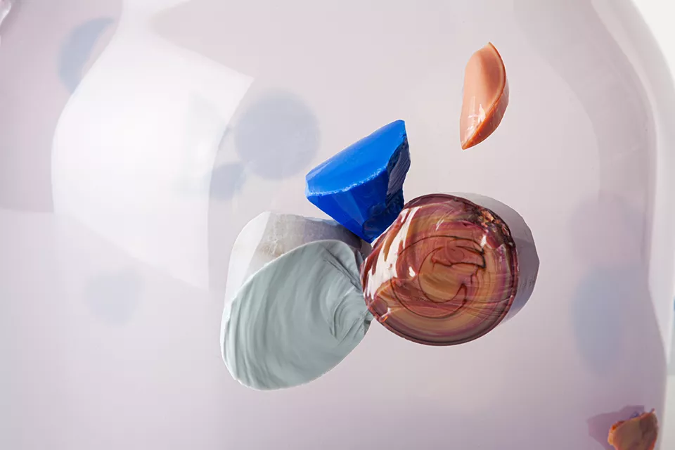 Colorful abstract gemstones floating around transparent sphere.