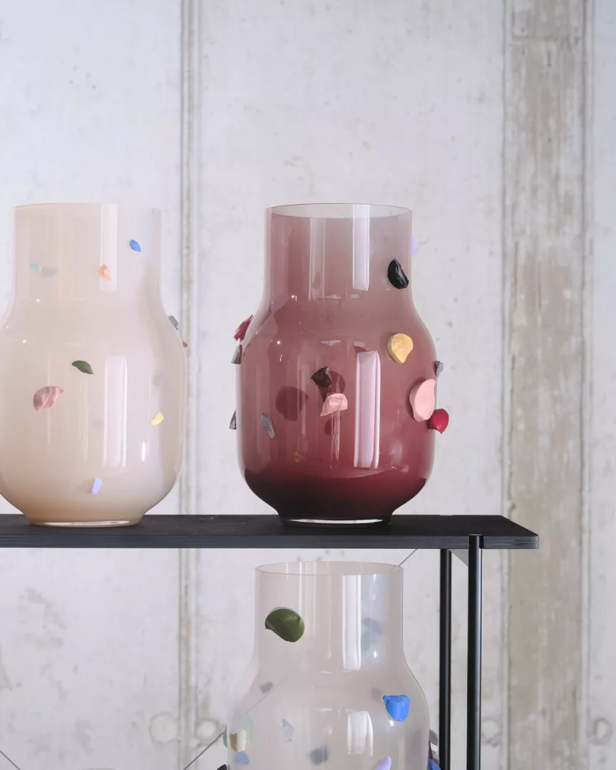 Colorful glass vases with embedded stones on display shelf.