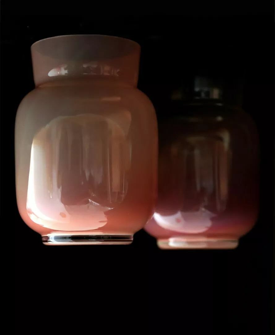 Two glass jars with pink liquid, black background.