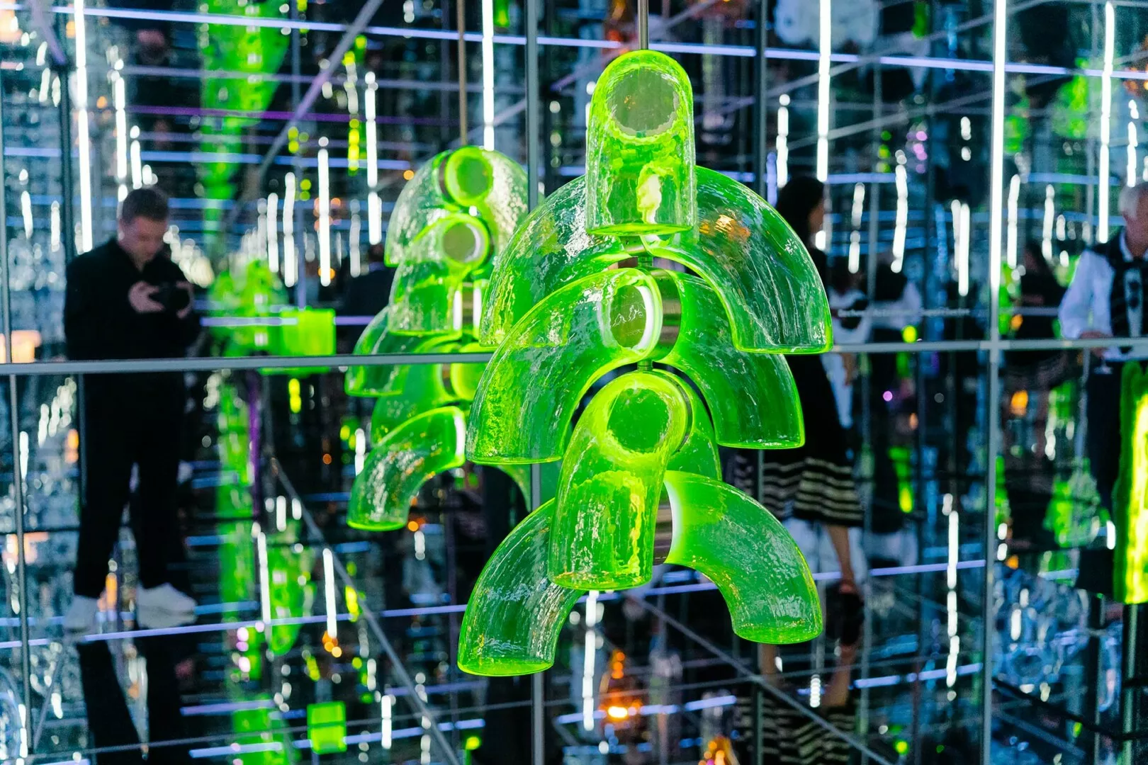 Green glass sculptures in a reflective art installation.