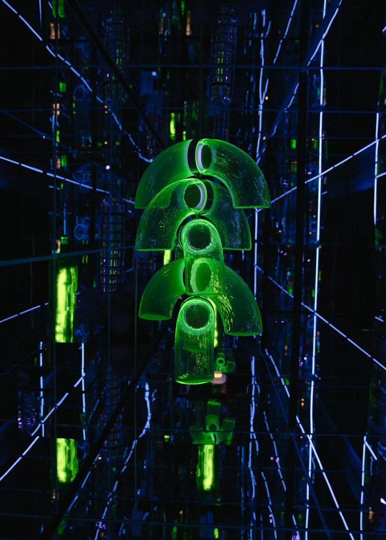 Neon green sculpture in futuristic mirrored corridor.