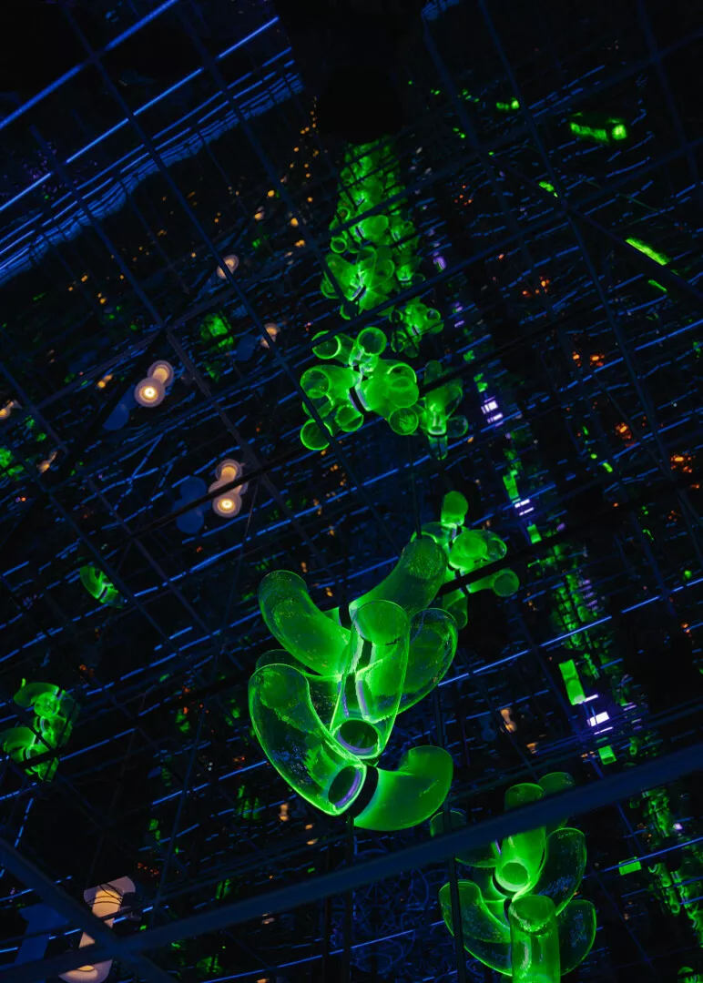 Neon green abstract art installation against dark grid backdrop.