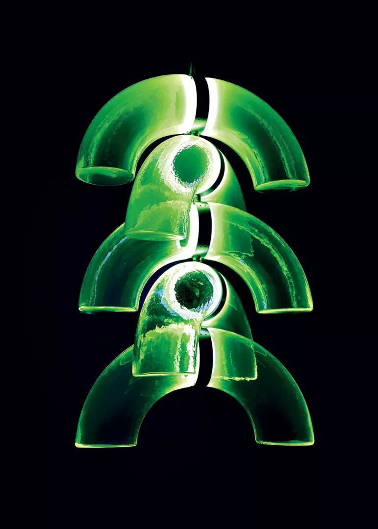 Green abstract curved glass sculpture on black background.