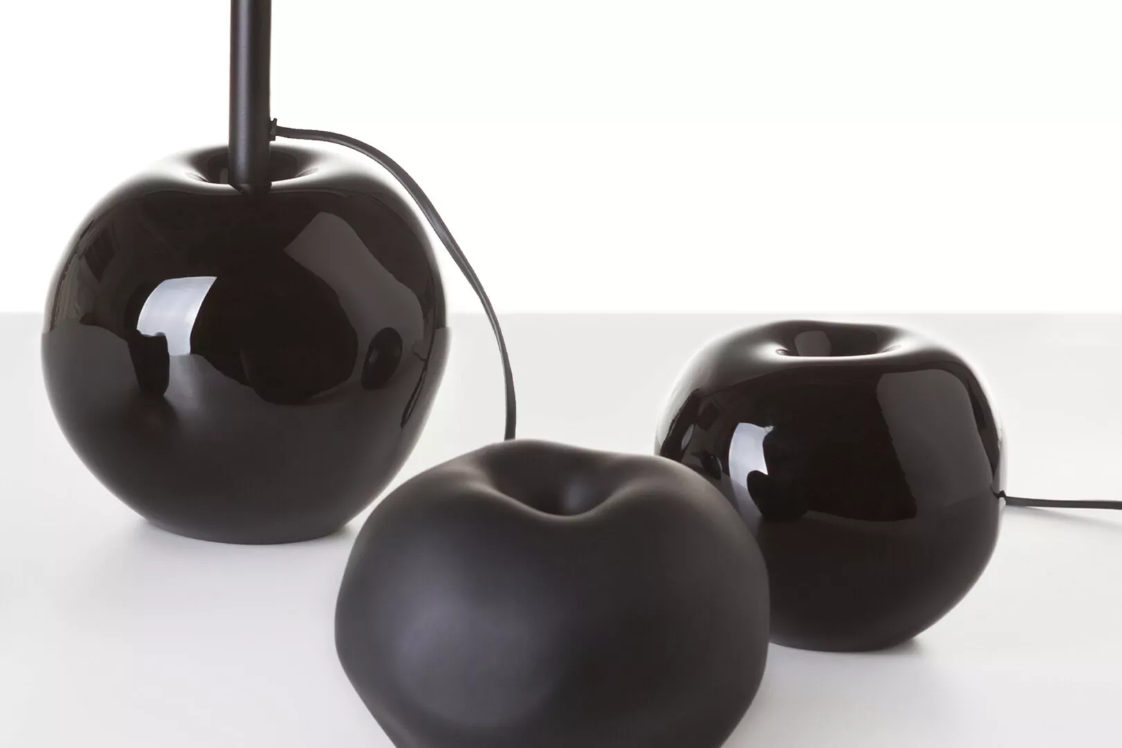 Glossy black apples on white background.