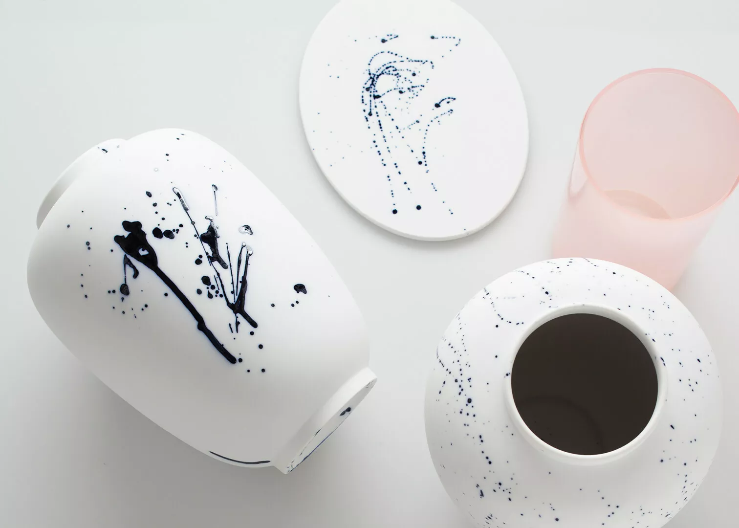 Minimalist ceramic vases and plates with blue splatter design.