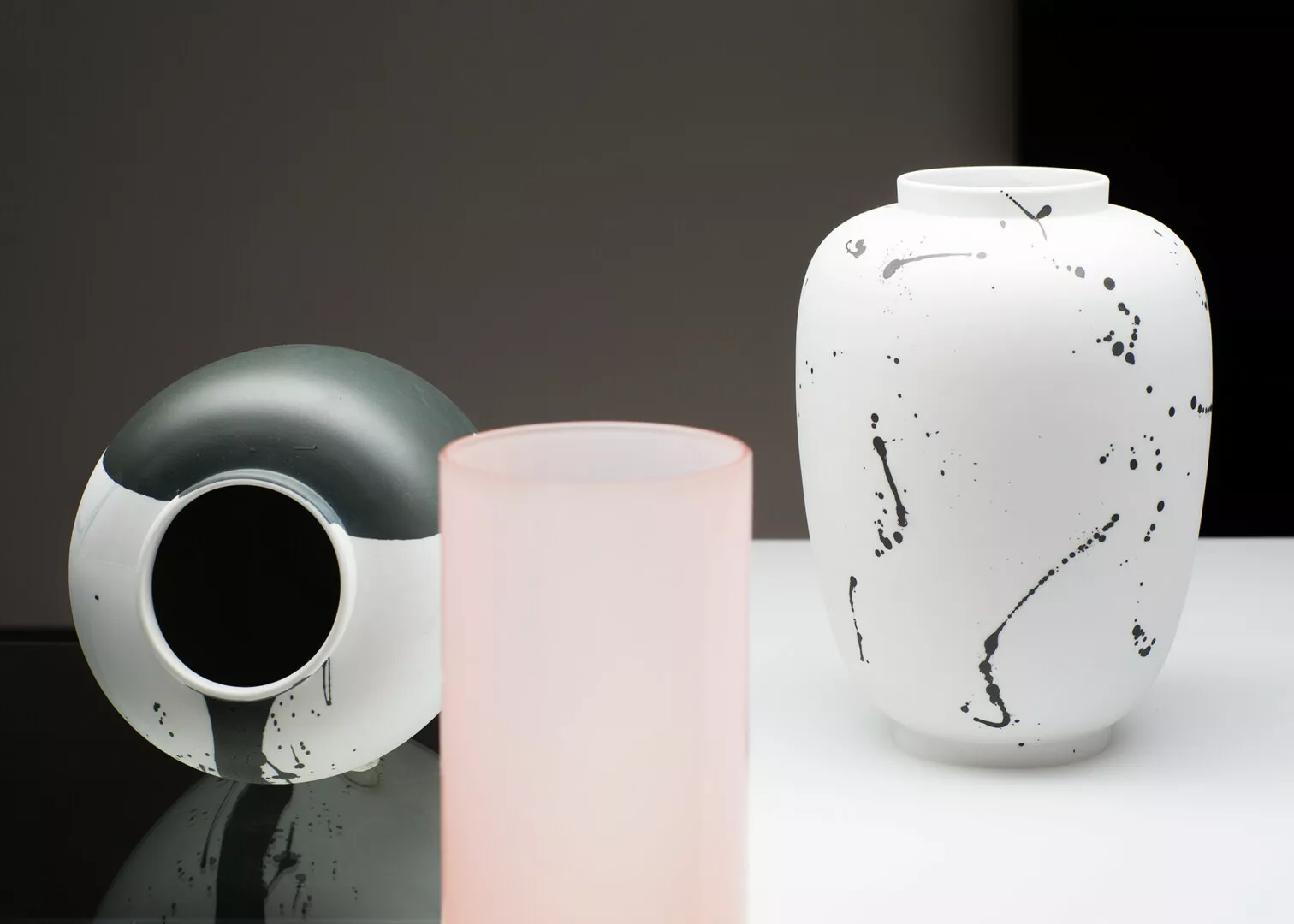 Three modern vases on reflective surface, artistic design.