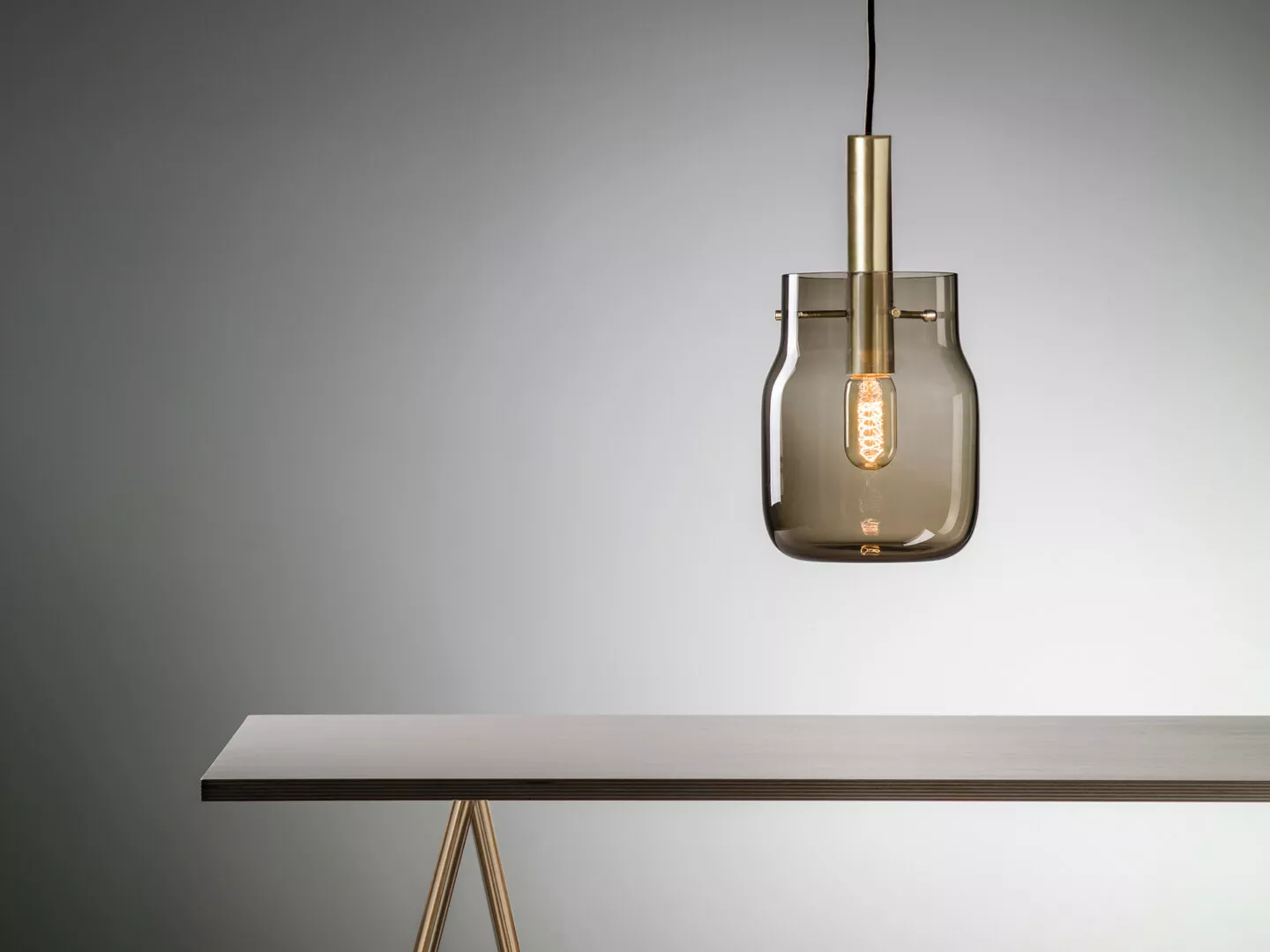Minimalist pendant light over gray table.