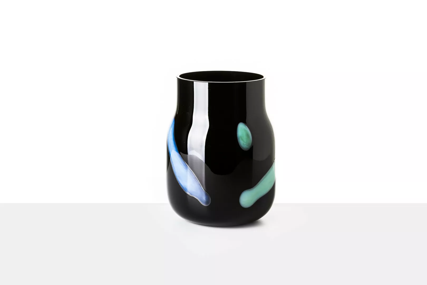 Black vase with abstract blue and green designs.