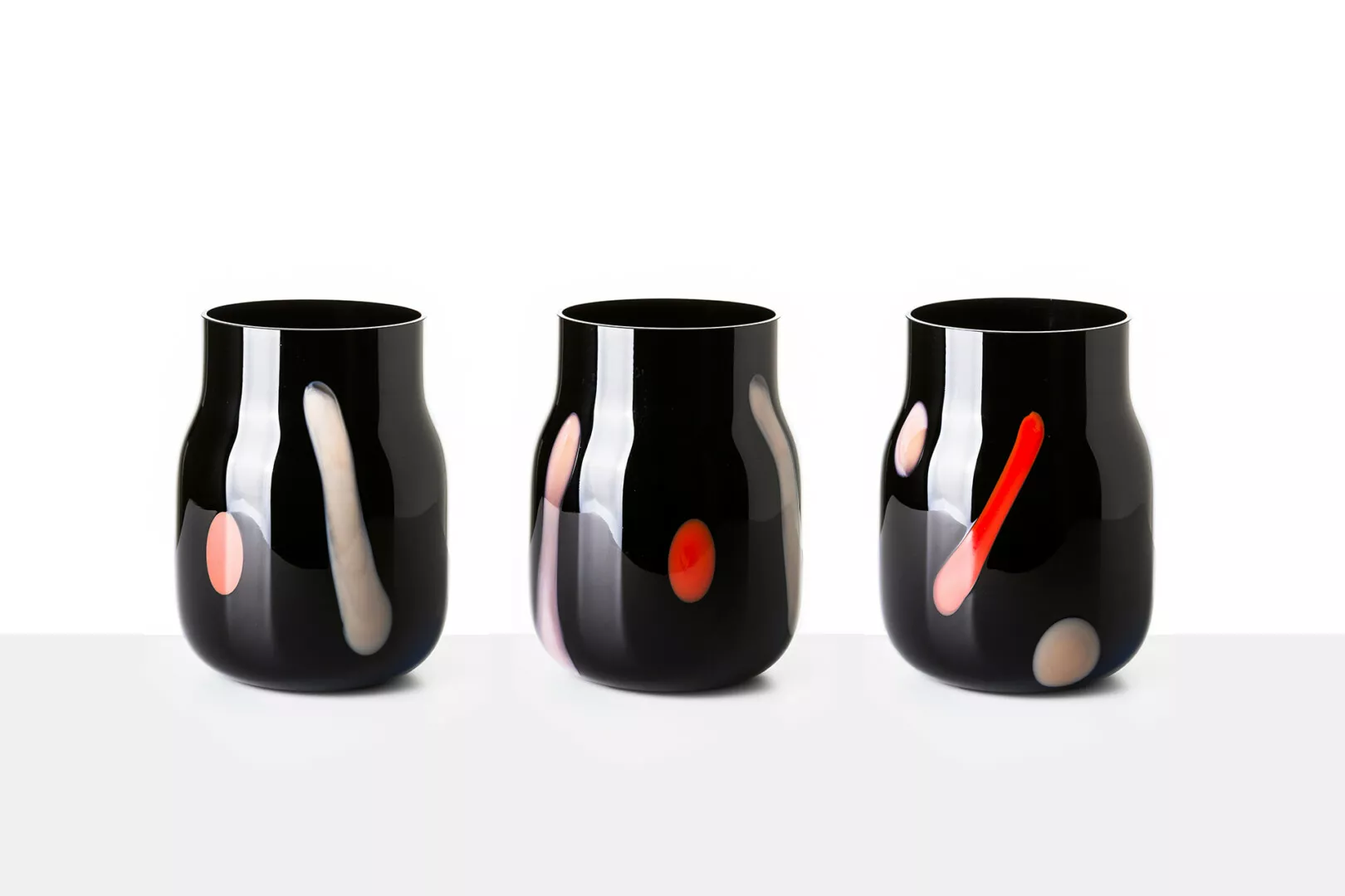 Three black contemporary vases with colorful abstract accents.