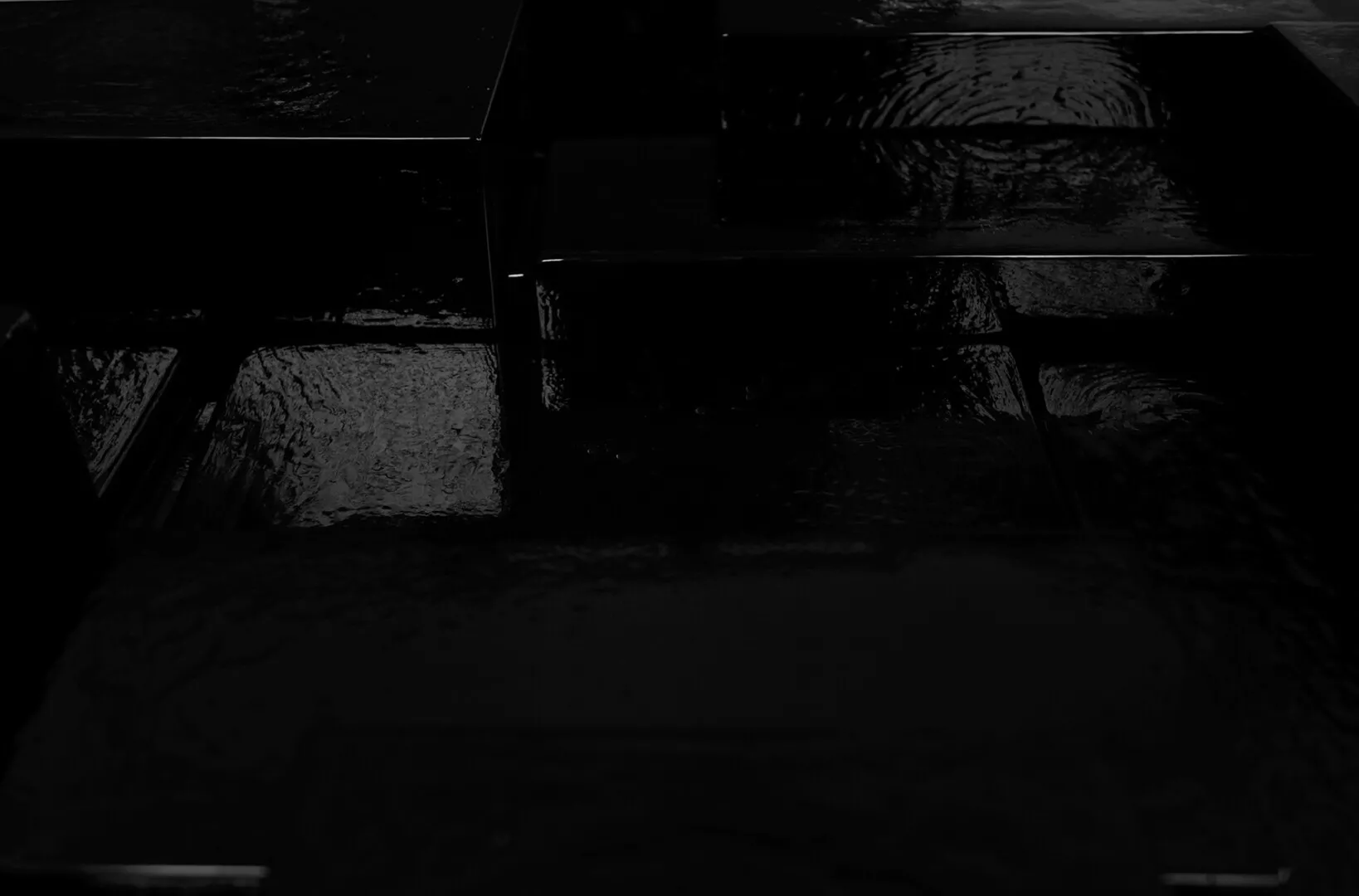 Abstract black tiles reflecting light, dark atmospheric background.
