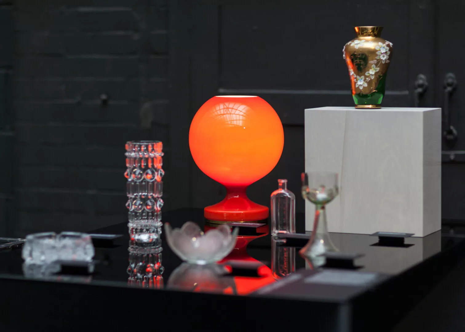 Red glowing lamp and assorted glass decor on table.