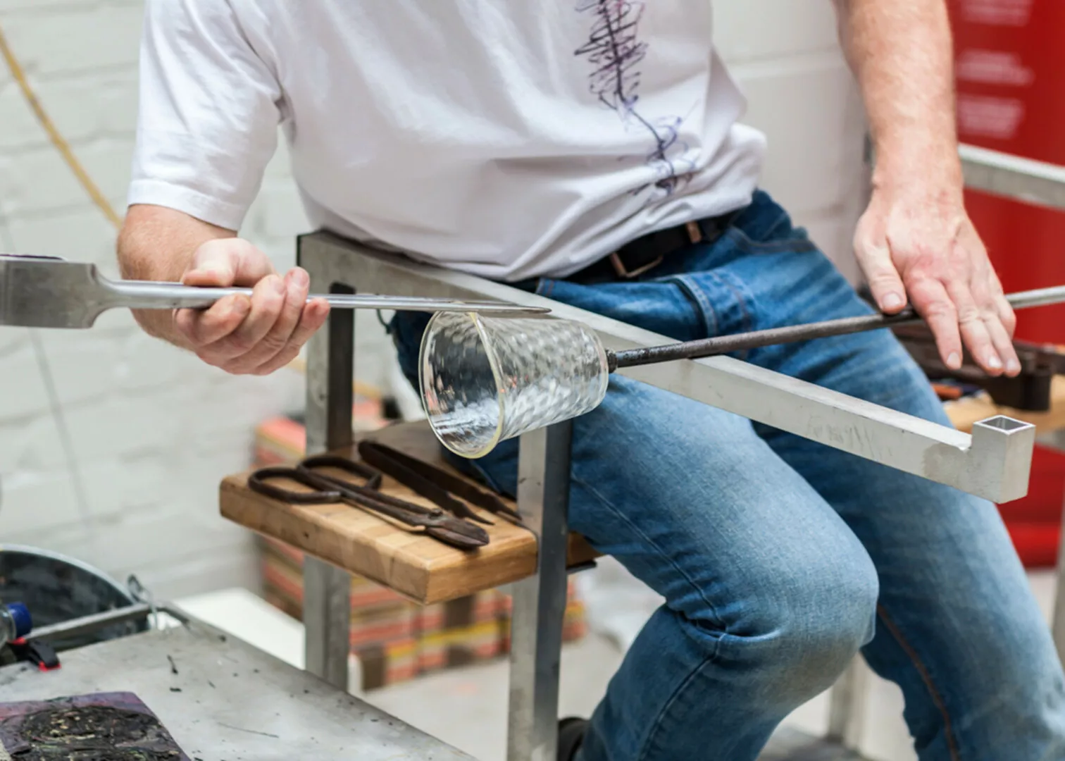 Glassblower shaping a glass vase at workshop.