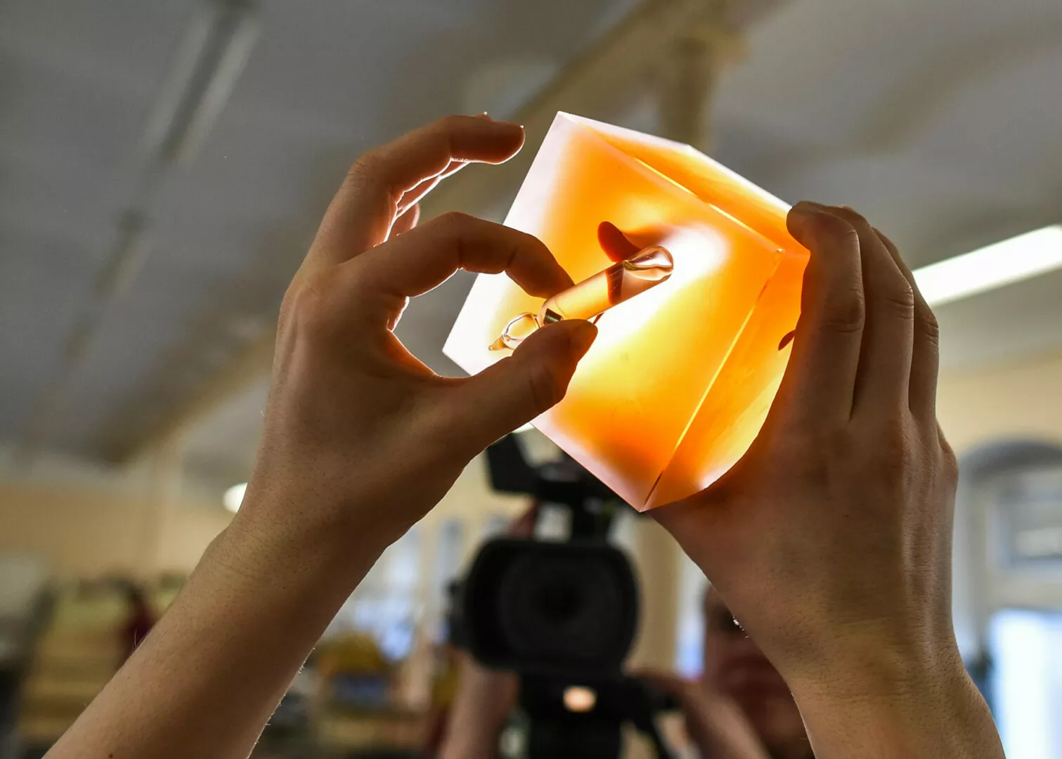Person examining illuminated cube in workshop.