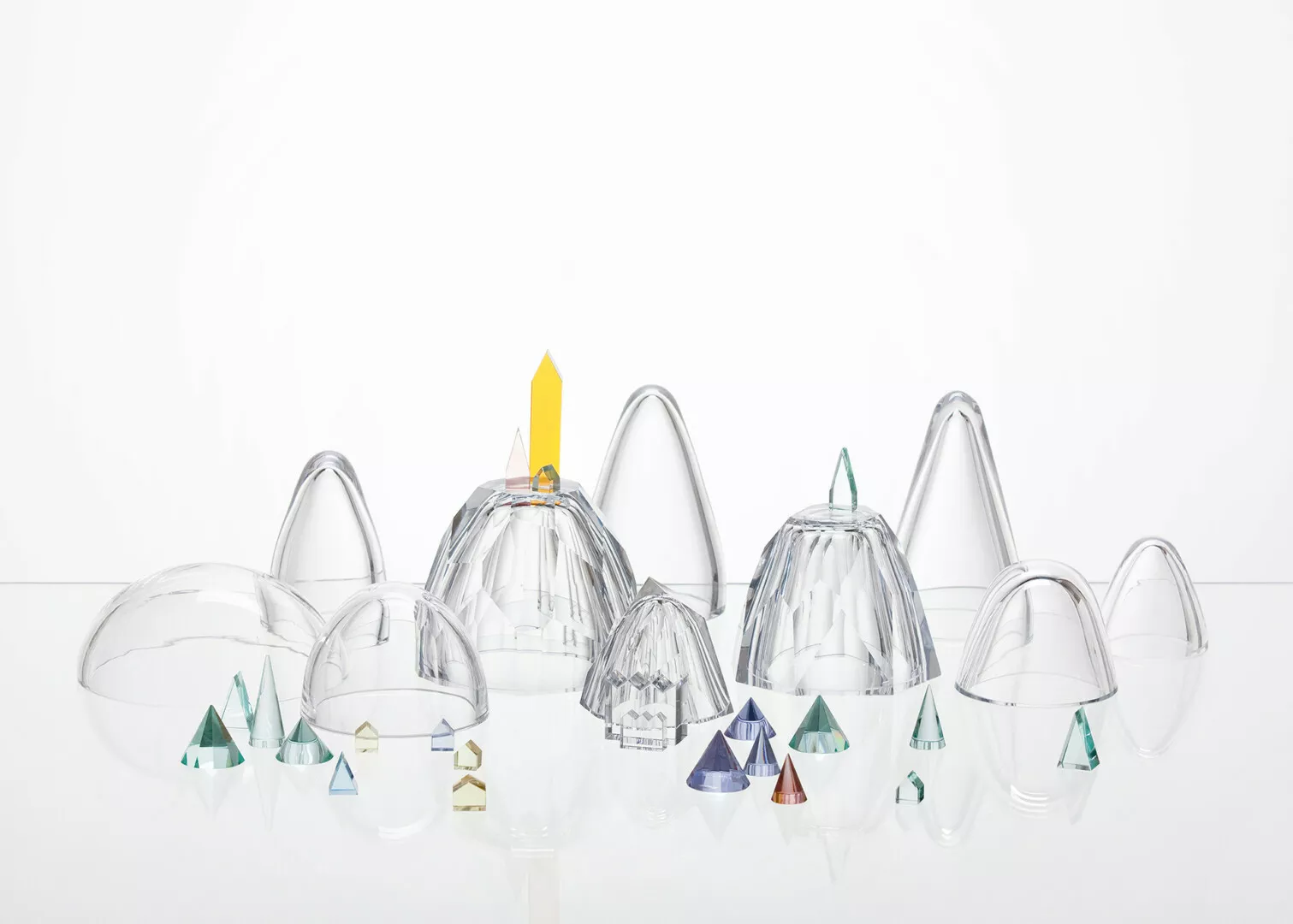 Transparent glass domes and geometric sculptures on white surface.