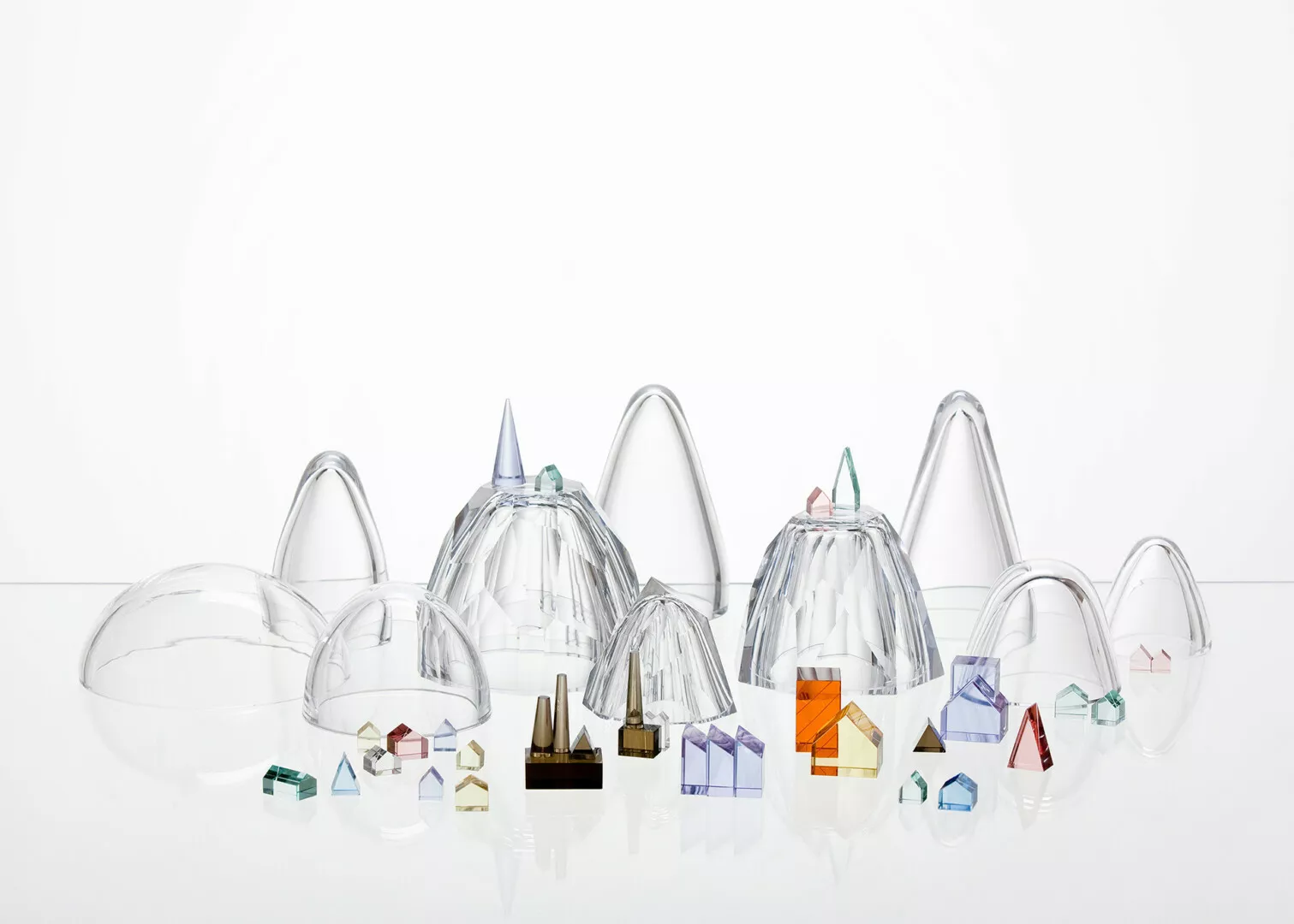 Clear glass domes and colorful geometric crystals on white.