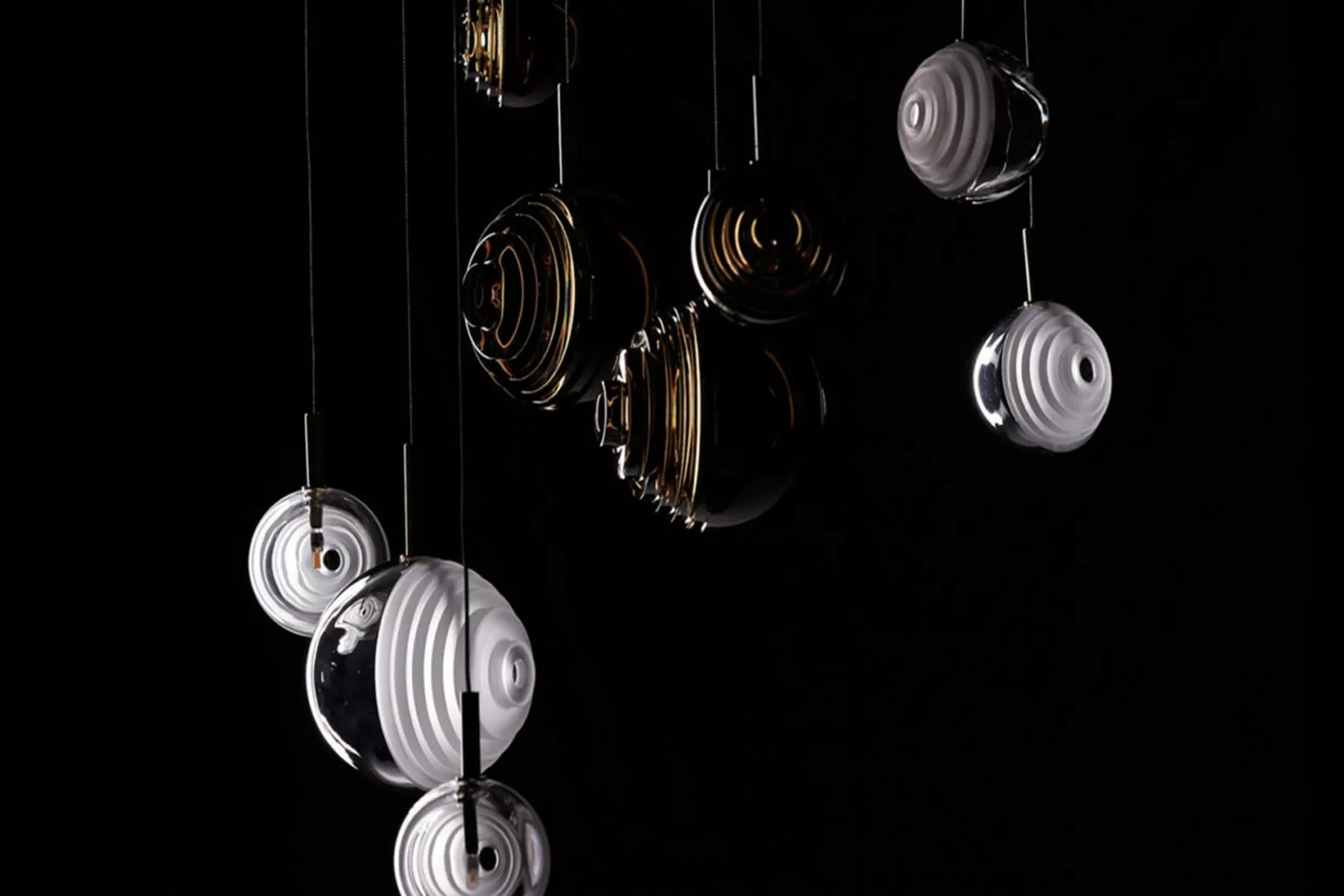 Suspended metallic orbs in varying designs against black.
