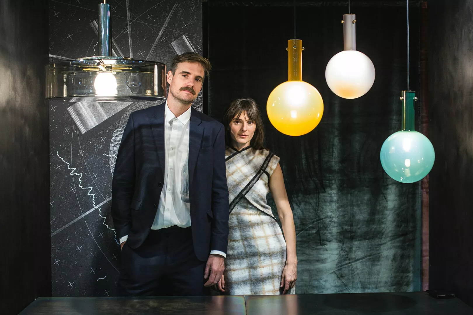 Elegant couple posing with colorful pendant lights.