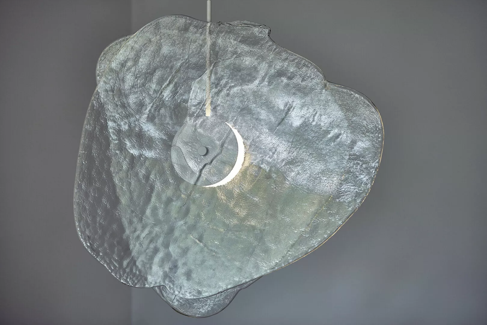 Textured glass pendant light against gray background.
