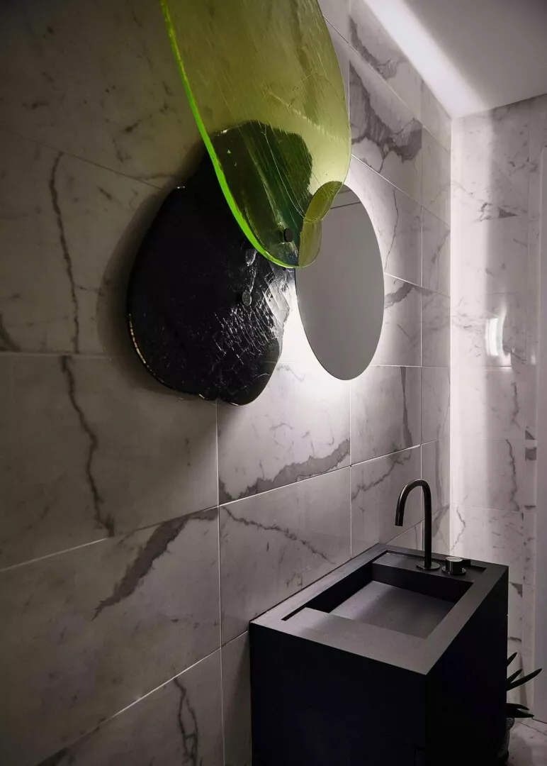 Modern bathroom with marbled walls and unique green sink.