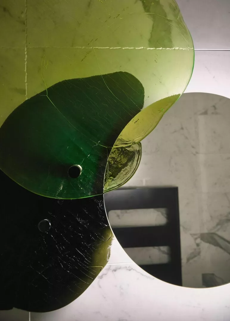 Abstract green glass art installation with mirror reflection.