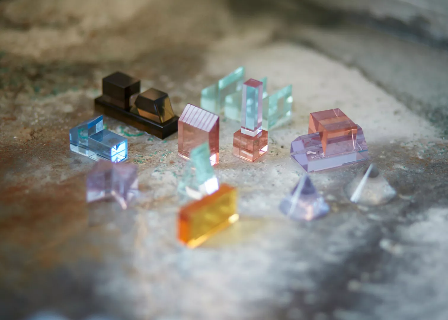 Assorted colorful crystal prisms on textured surface.
