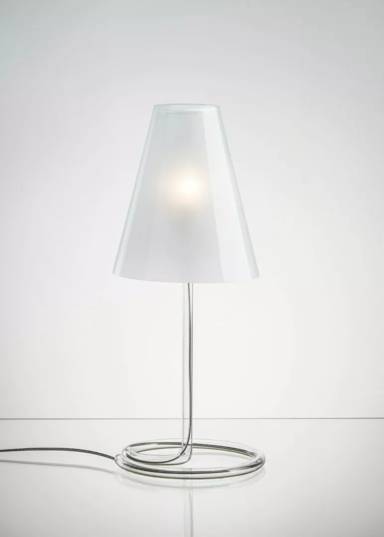 Modern lamp with illuminated bulb and transparent shade.