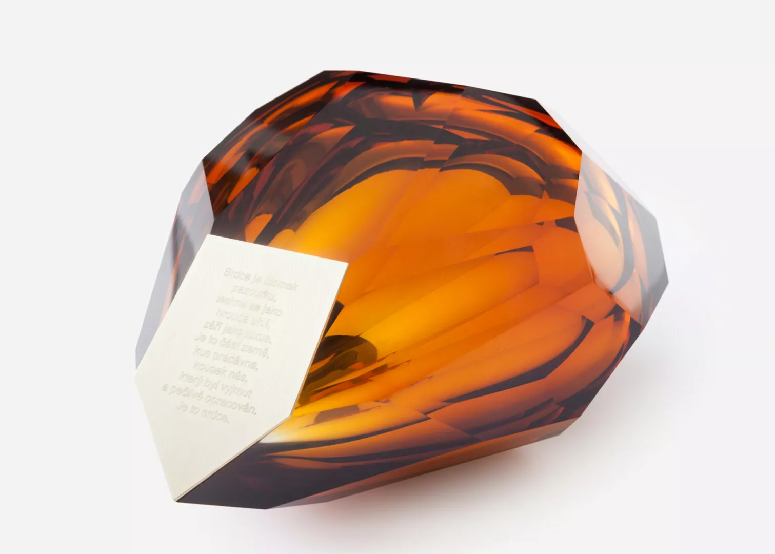 Amber-colored crystal sculpture with inscribed white note.