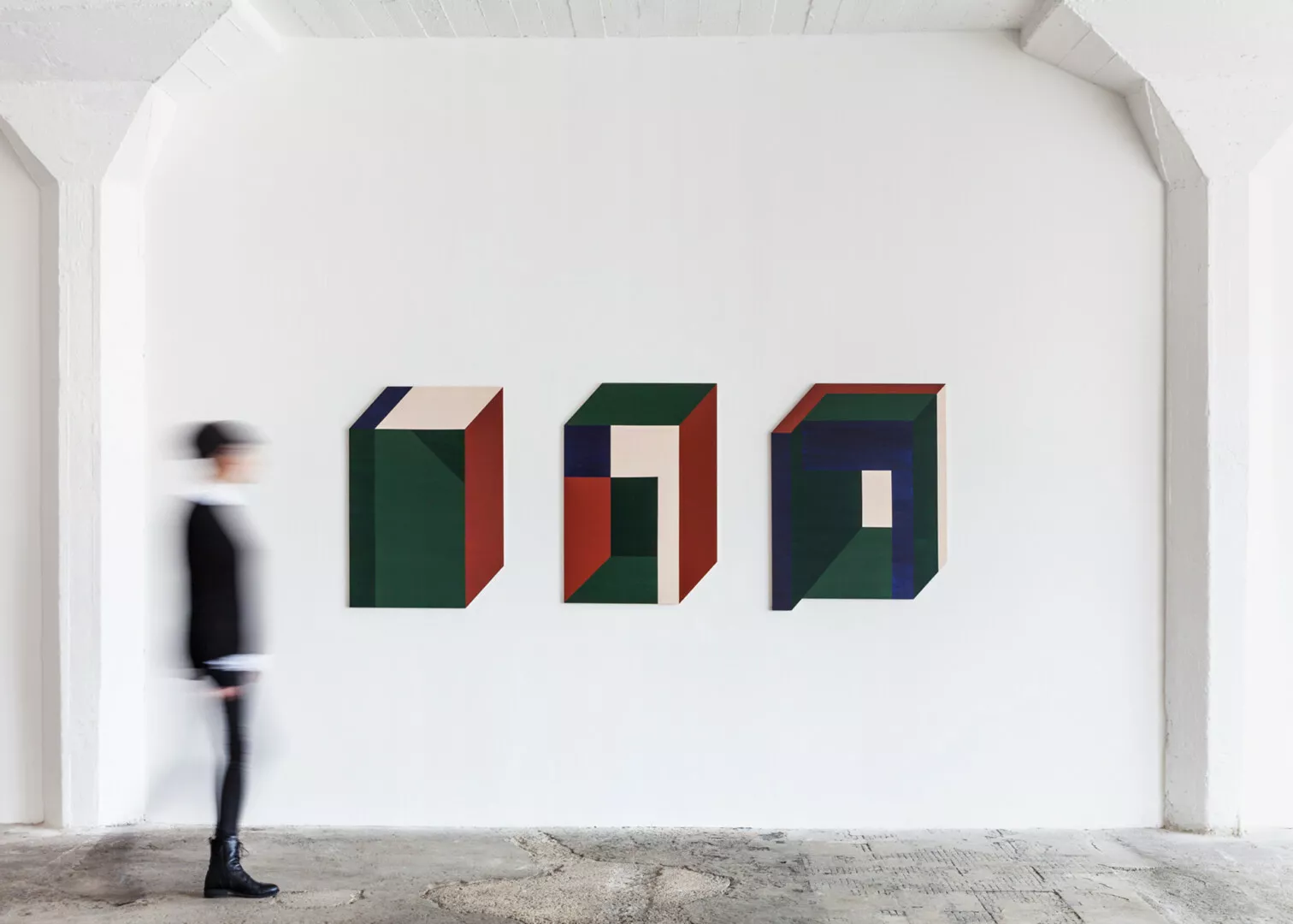 Blurry person walking past modern geometric wall art.