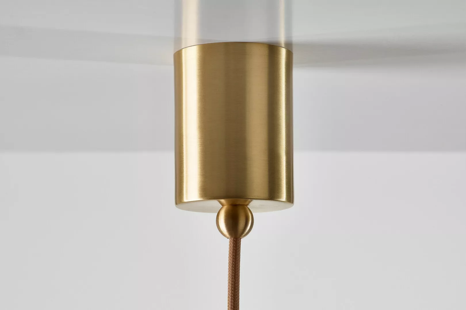 Gold pendant light with clear cylinder cover.