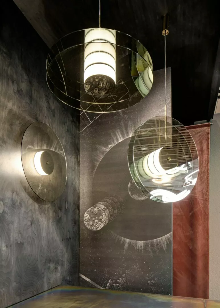 Ceiling lamps reflecting in mirrored cosmic-themed panels.