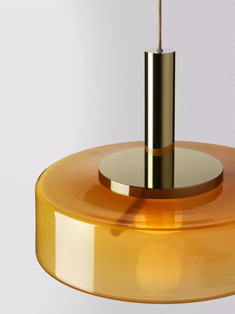 Modern gold pendant light with amber glass shade.