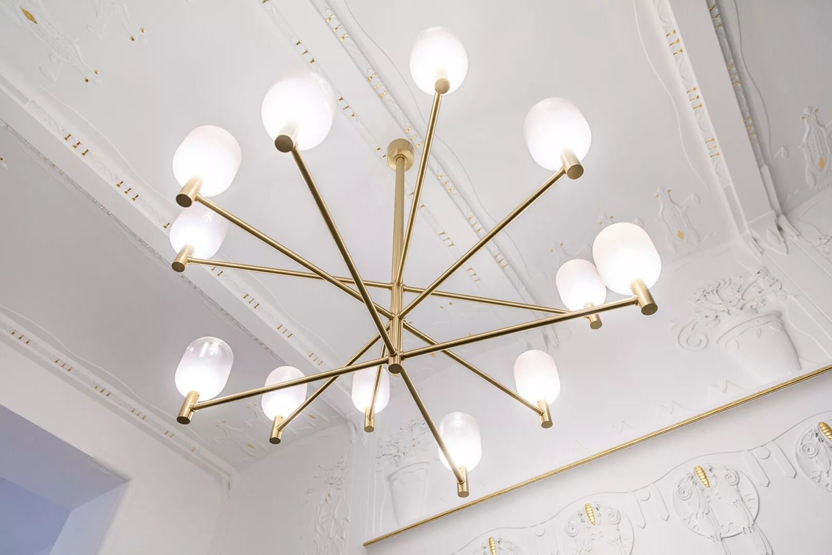 Modern chandelier with orbs in ornate white room.