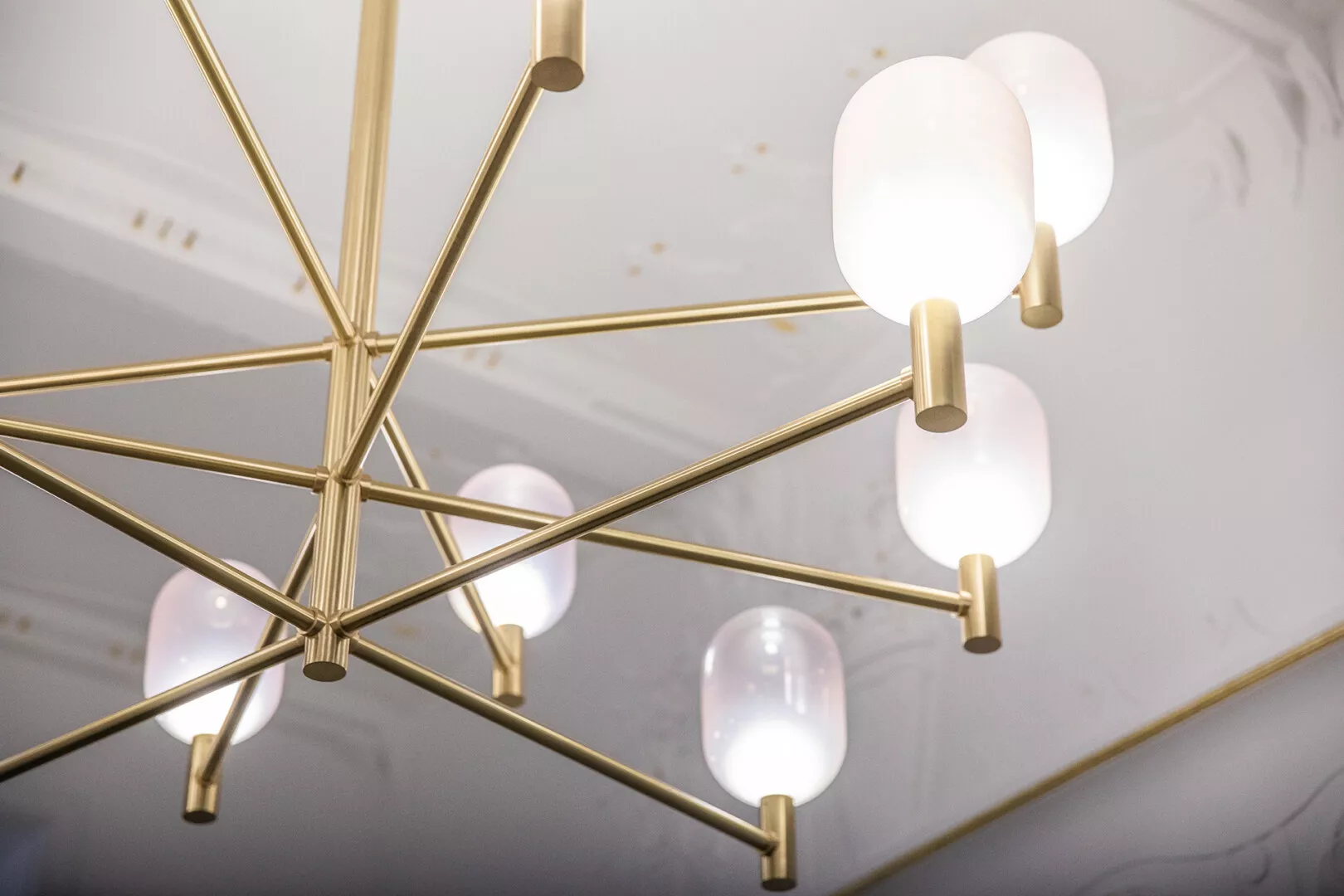 Modern gold geometric chandelier with glowing white bulbs.