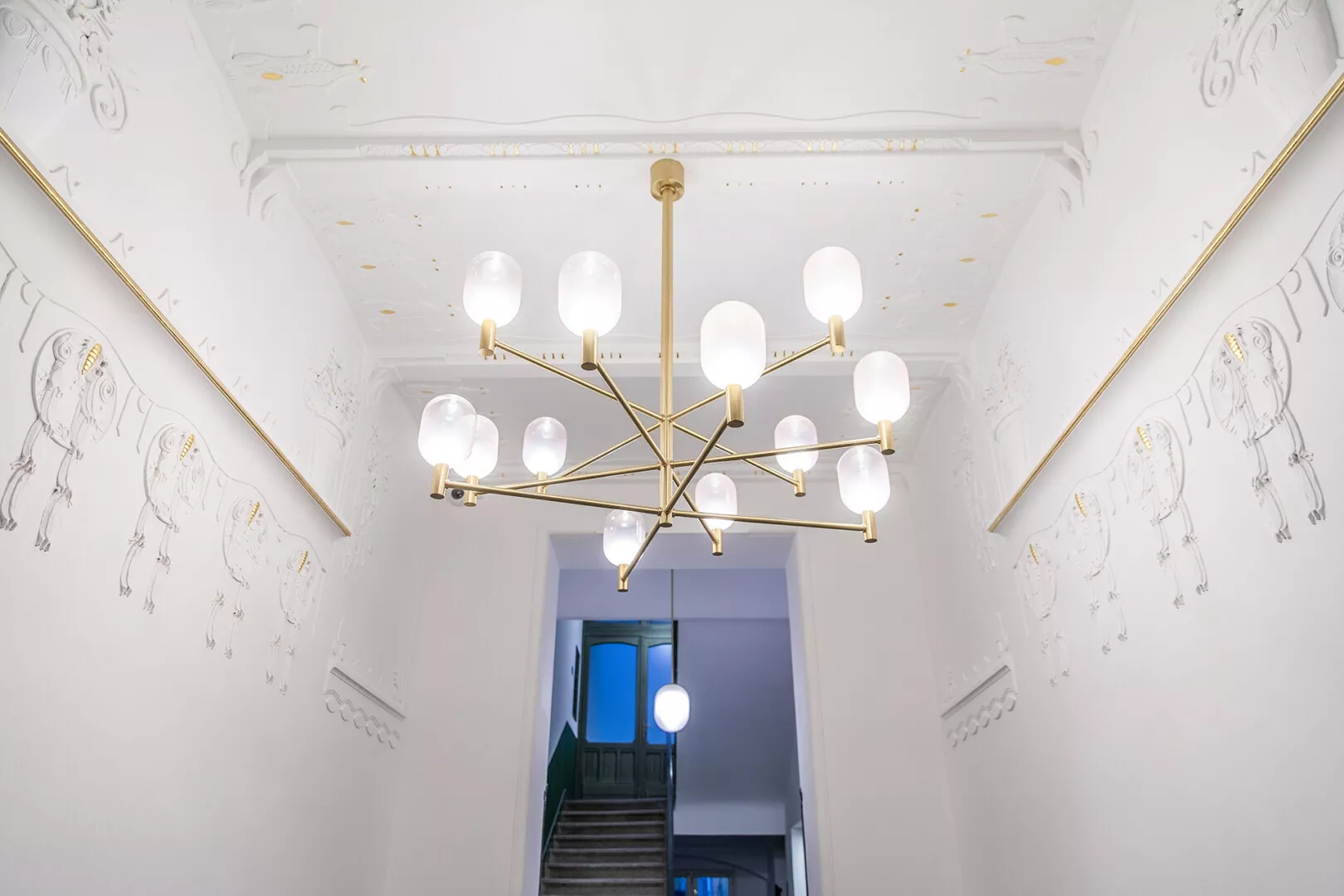 Elegant chandelier in a modern hallway with artistic ceiling design.