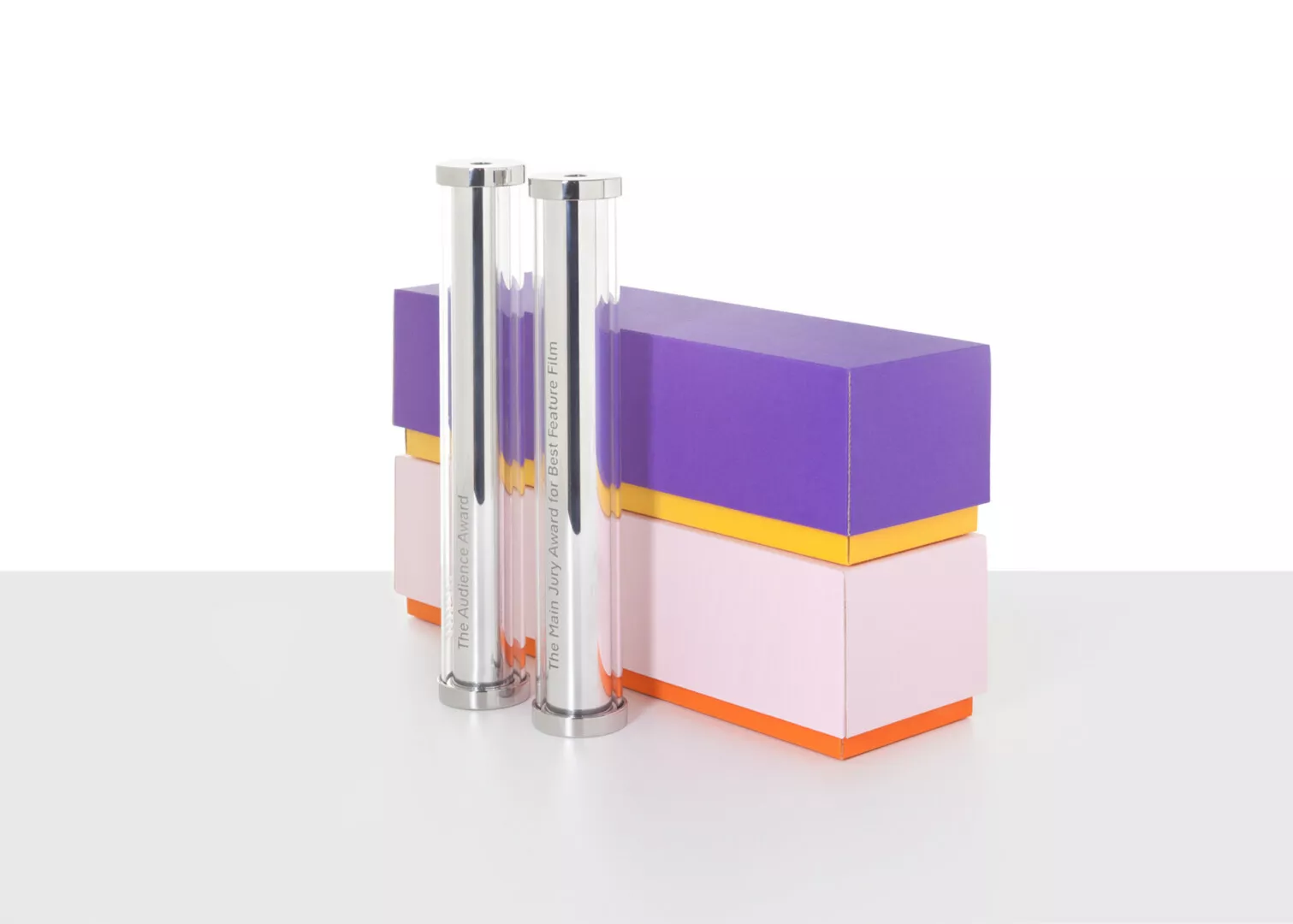 Colorful award trophies on stacked boxes, minimalist background.