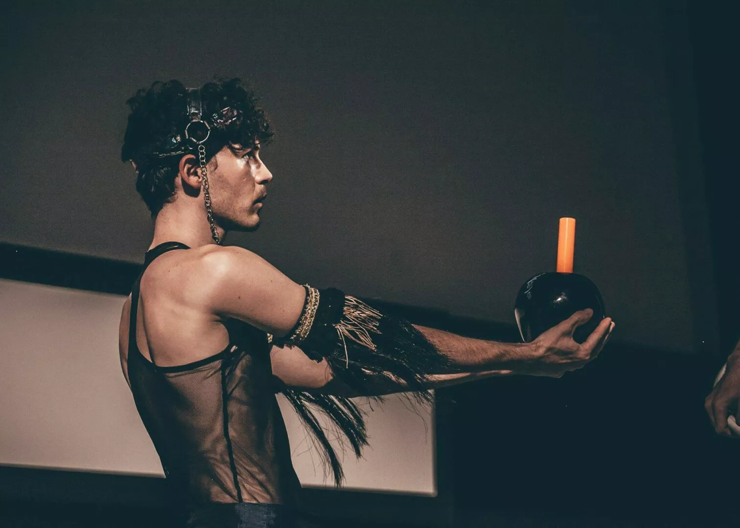 Man in costume holding glass sphere in dim lighting.