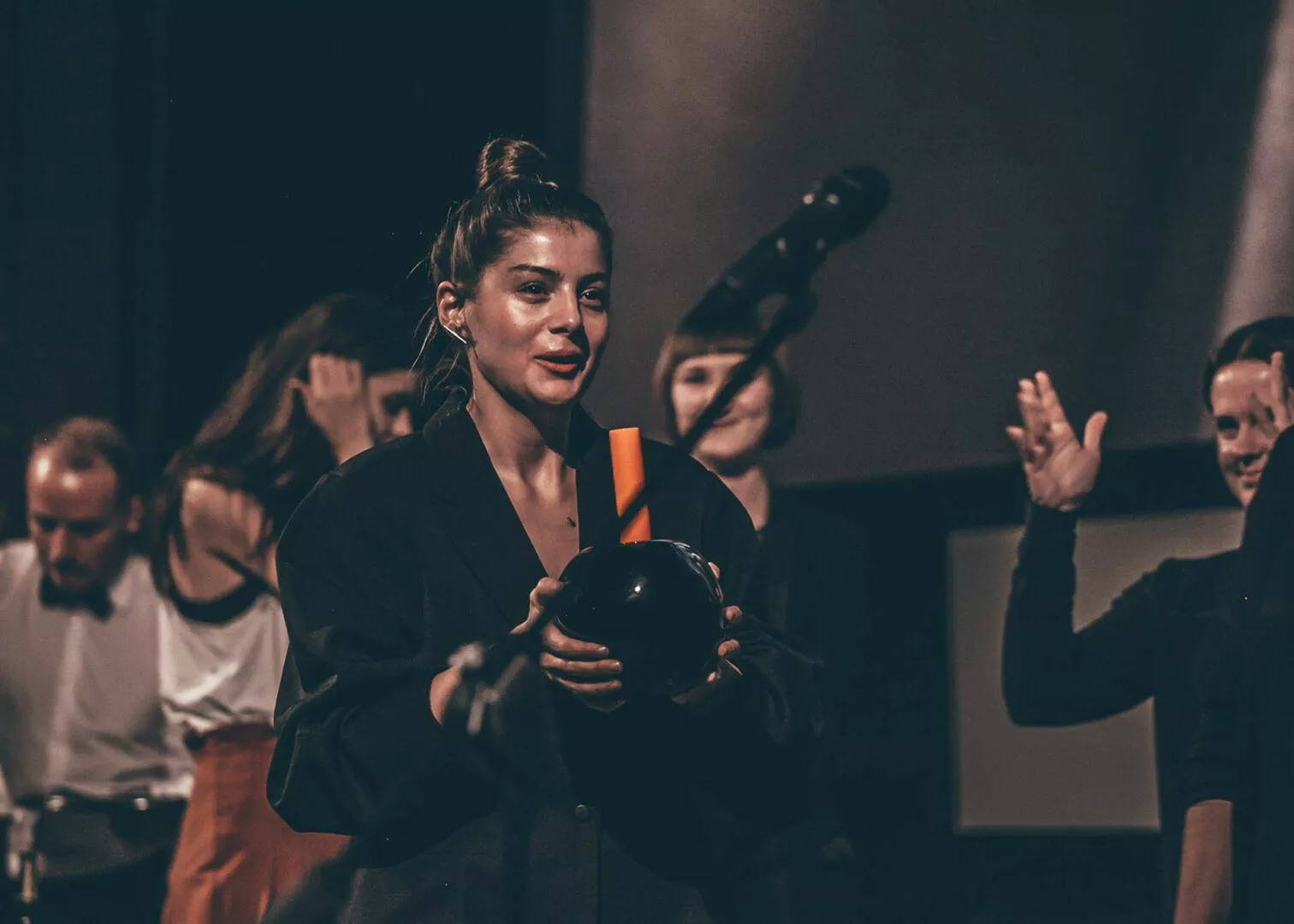 Woman performing with black bowling pin onstage.