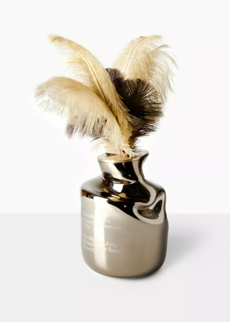 Feather quill in shiny trophy inkwell on white background.