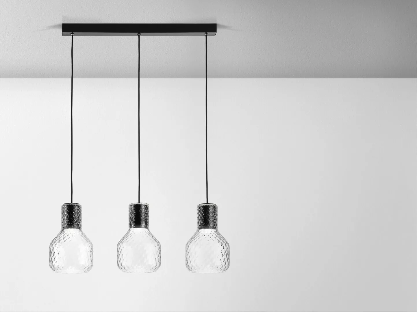 Three textured glass pendant lights hanging against white background.