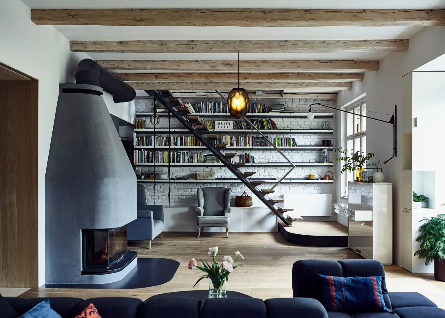 Modern living room with fireplace and suspended staircase.