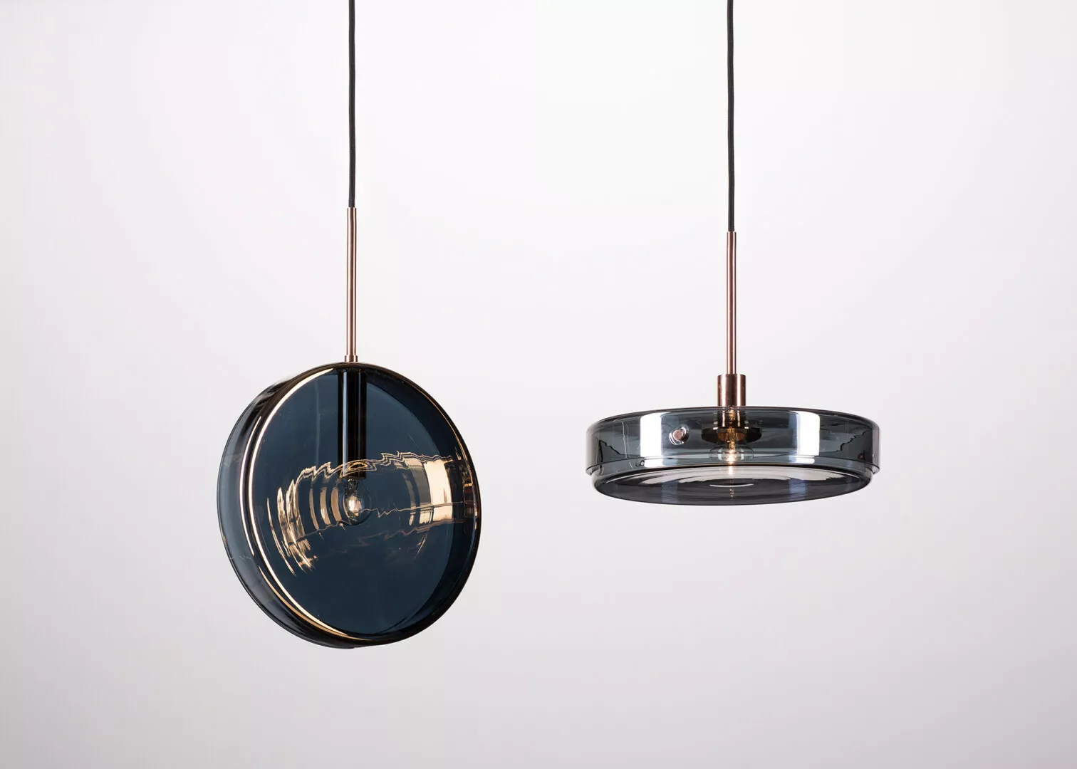 Modern pendant lights with reflective copper and glass design.