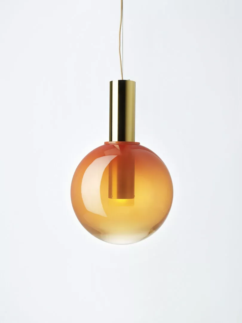 Modern orange gradient pendant light against white background.