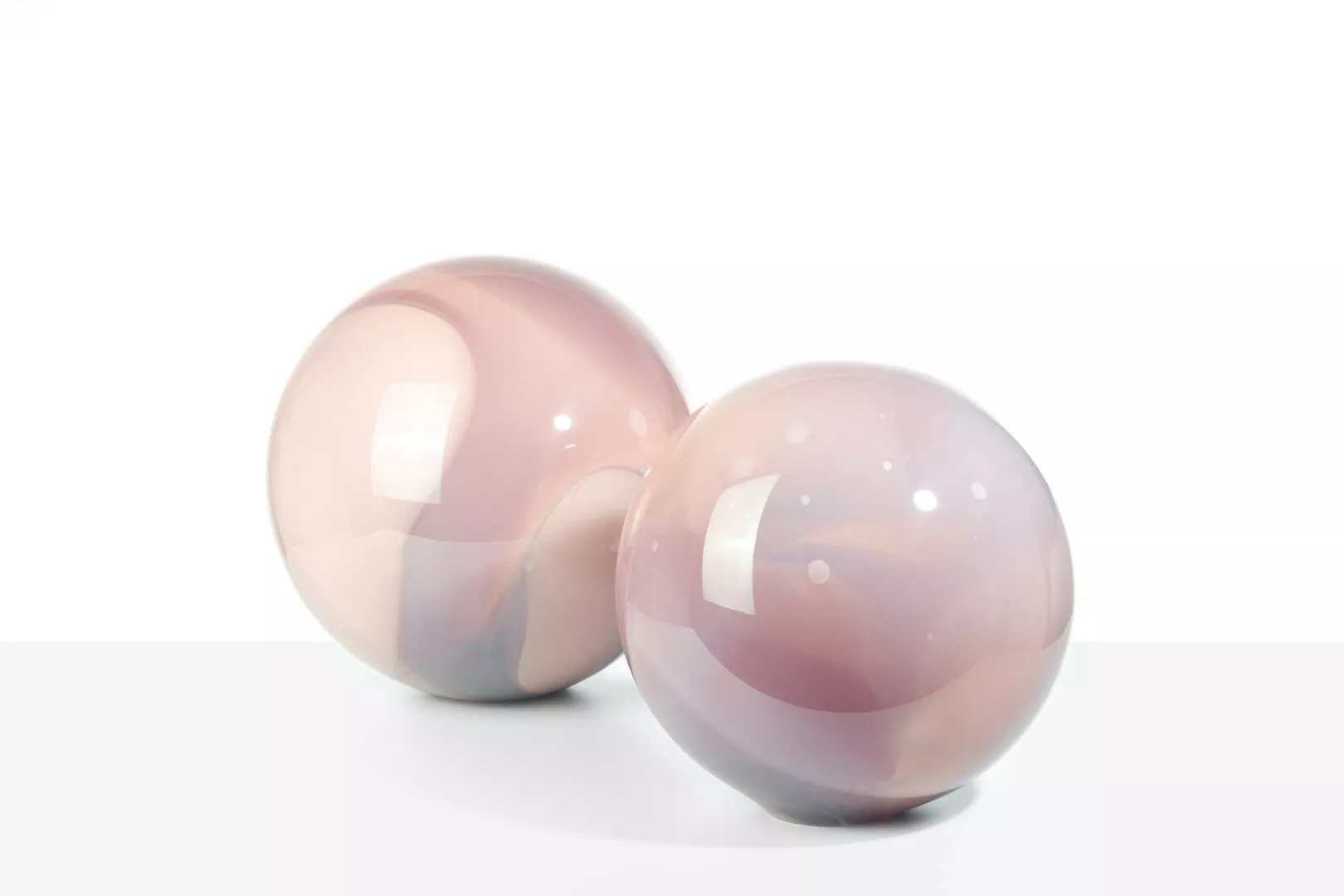 Two pink glass spheres on a white background.
