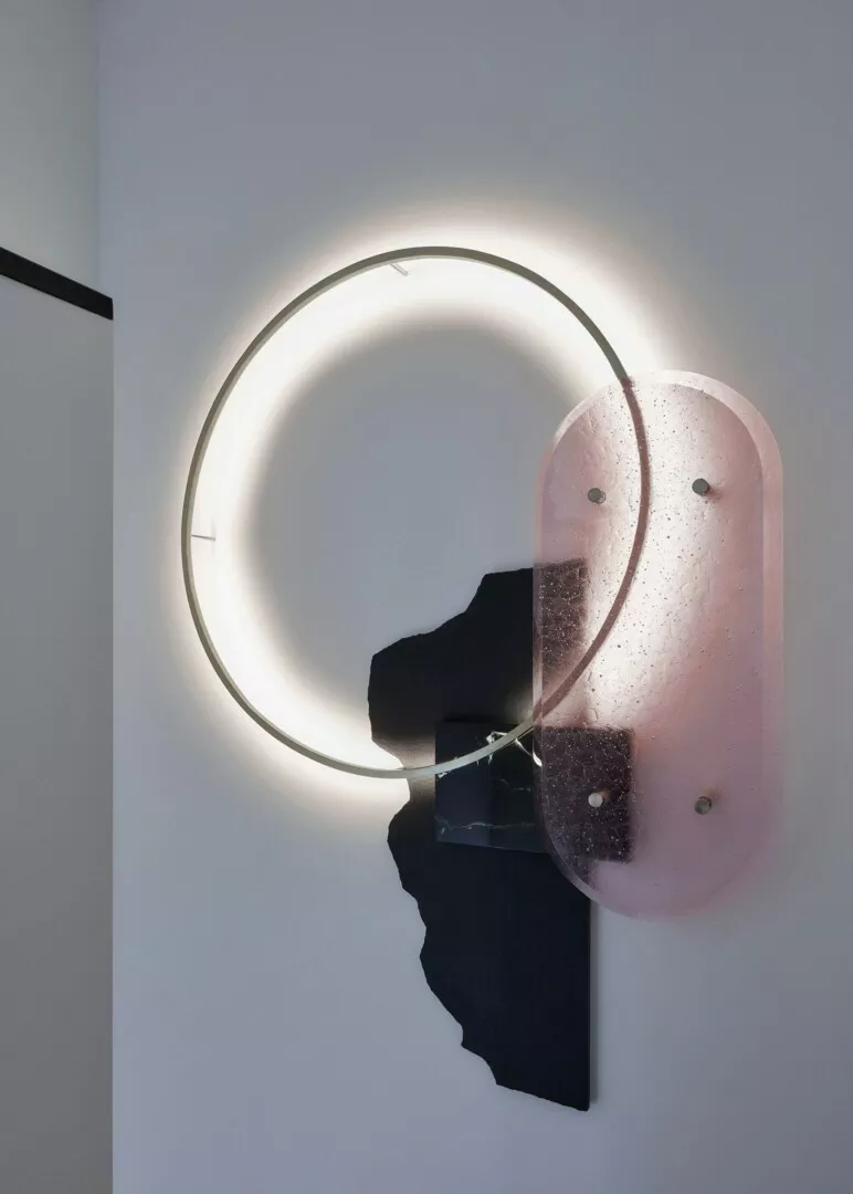 Modern circular wall light with pink glass accents.