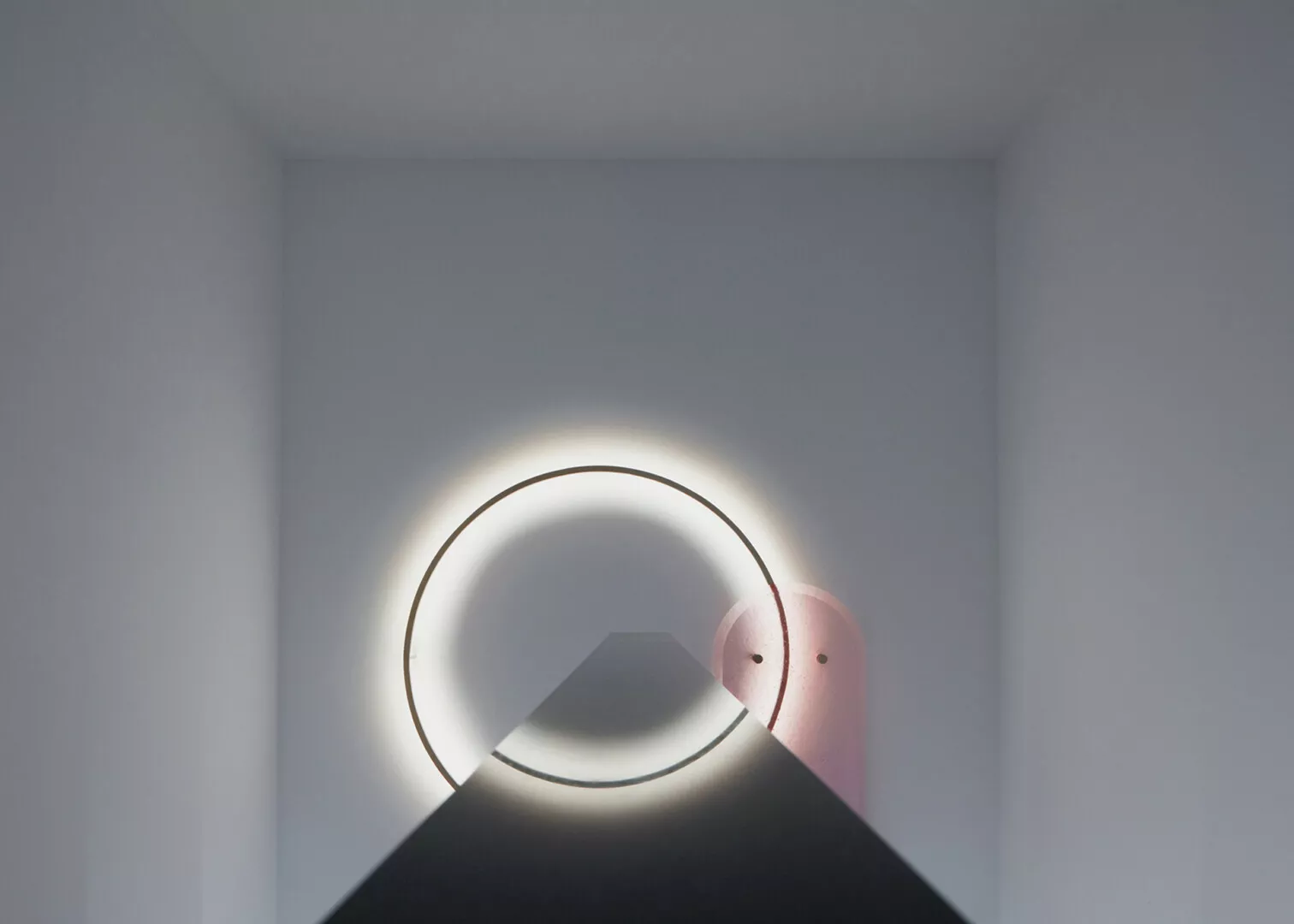 Circular LED light in minimalist white room.