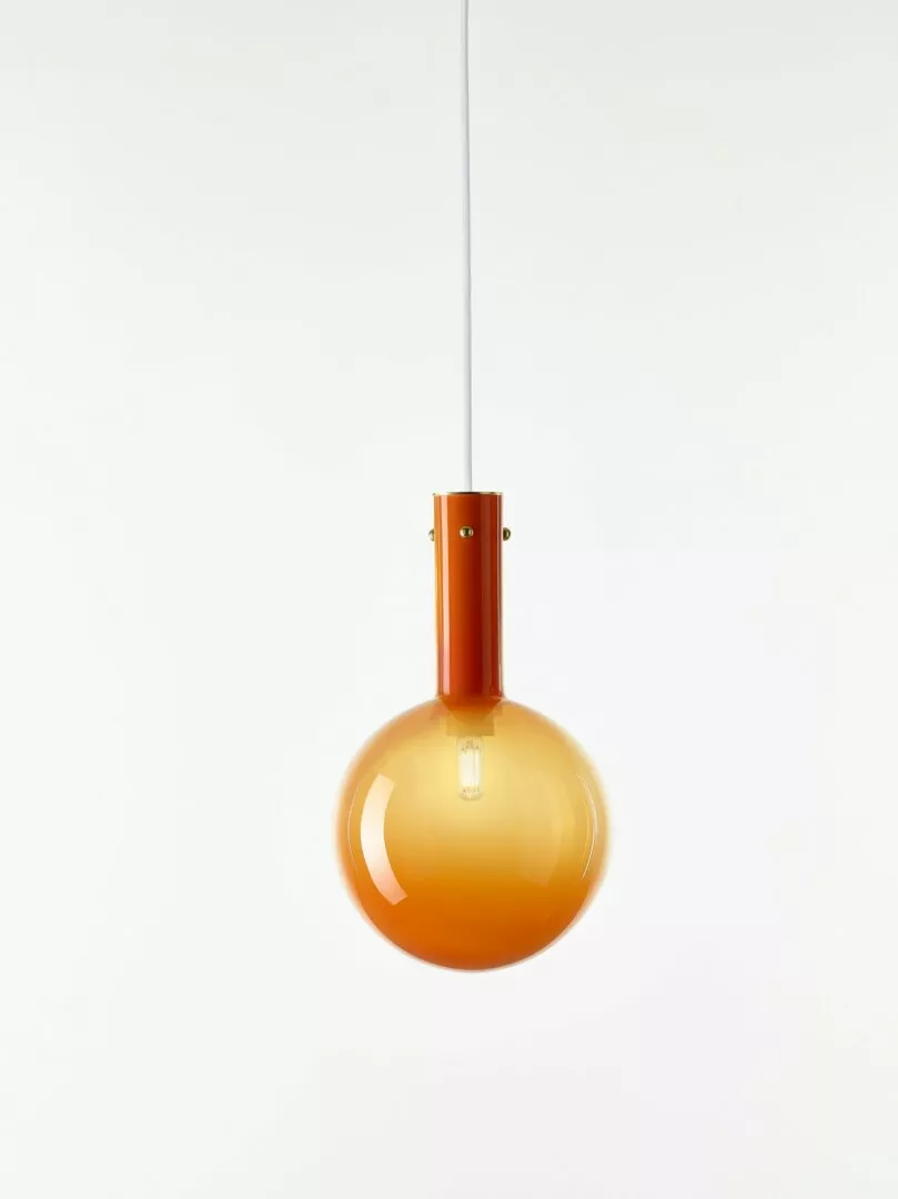 Amber glass pendant light hanging against white background.